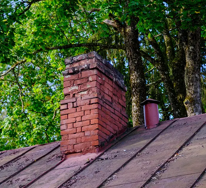 Old brick chimney in need of repair on a roof